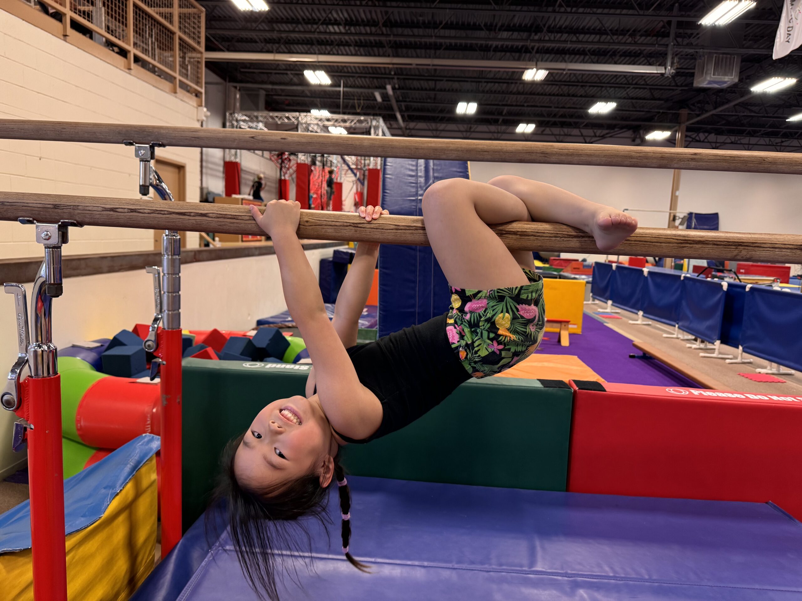 young girl hanging on gymnastics bars